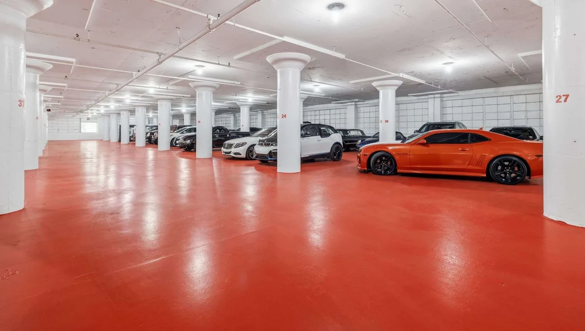 Indoor vehicle storage with luxury cars, white support columns and polished red concrete floor